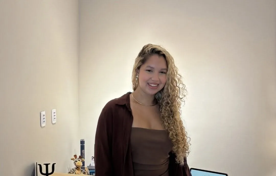Lorrayne Ísis no consultório, ao lado da mesa de atendimento