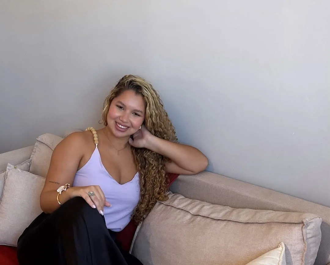 Retrato de Lorrayne Ísis, psicóloga, sentada em um sofá